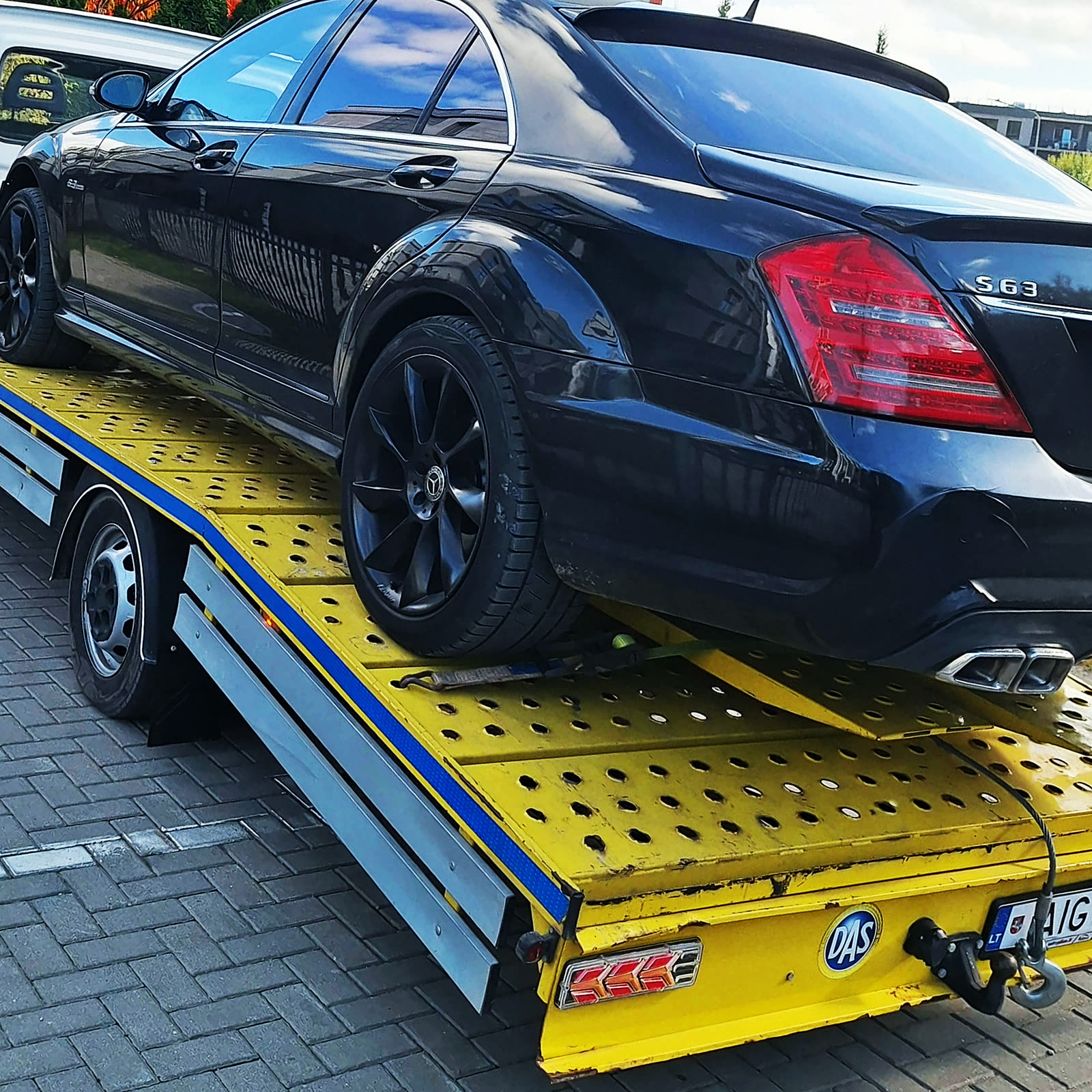 Iš arti: automobilio galas ir geltona platforma su mėlynu kraštu
